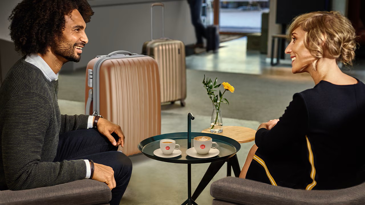 twee gasten in de receptie van een hotel drinken koffie
